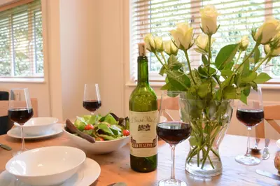 a table with a bottle of wine and a vase of flowers at Town Farm House, Orford in Orford