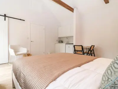 a white bedroom with a large bed and chairs at Town Farm House, Orford in Orford