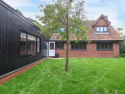 a black house with a tree in the yard at Town Farm House, Orford in Orford