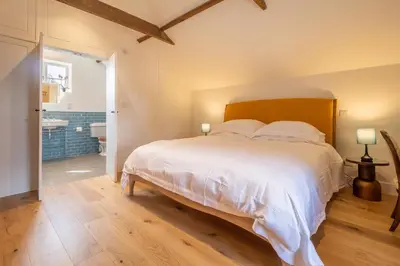 a bedroom with a large bed and a bathroom at Luxurious rural retreat - Holt Coach House in Sudbury