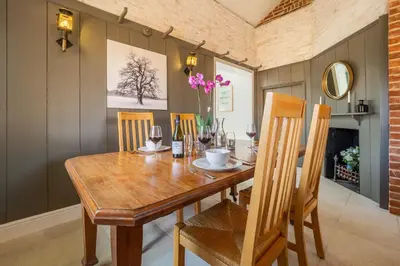 a dining room with a wooden table and chairs at Luxurious rural retreat - Holt Coach House in Sudbury