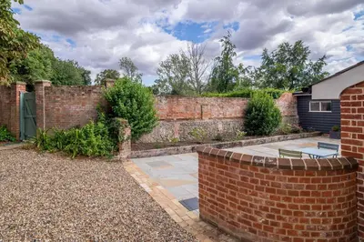 a brick wall with a patio in a yard at Luxurious rural retreat - Holt Coach House in Sudbury