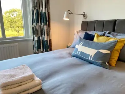 a bedroom with a blue bed with pillows and a window at 72 Ashley Road in Newmarket