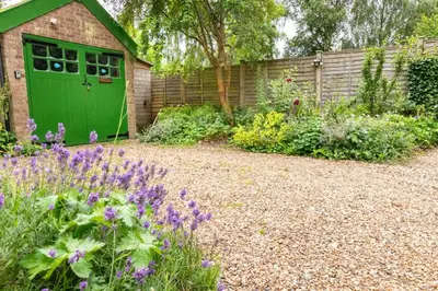 a green garage in a garden with purple flowers at 3 Bed in Yoxford oc-bmy in Yoxford
