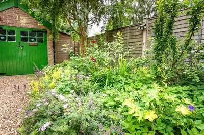 a garden with a green door and some flowers at 3 Bed in Yoxford oc-bmy in Yoxford