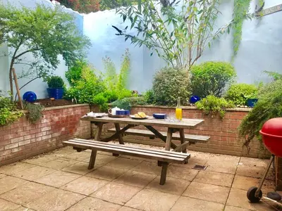 a wooden picnic table with a bench in a garden at The Red Brick House, Aldeburgh in Aldeburgh