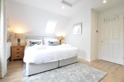 a white bedroom with a large bed and a door at The Red Brick House, Aldeburgh in Aldeburgh