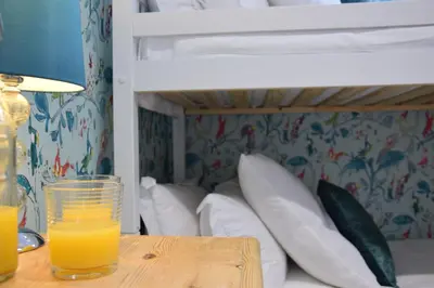 a glass of orange juice on a table next to a bunk bed at The Red Brick House, Aldeburgh in Aldeburgh