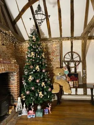 a christmas tree in a living room with a teddy bear at Grade II Listed Farmhouse, Pool, Hot Tub, Games Room, Celebration Hall, Car Park, 10ppl, 45 min from Central London in Stapleford Tawney