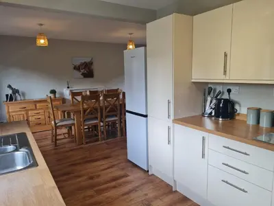 a kitchen with white cabinets and a dining room at The Farmhouse - Linton Horseheath in Linton