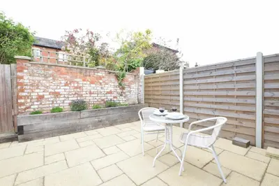 a patio with two chairs and a table and a fence at 1 Tailors Cottage, Woodbridge in Woodbridge