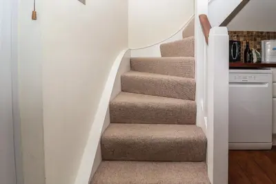 a staircase in a home with a white stair case at 1 Tailors Cottage, Woodbridge in Woodbridge