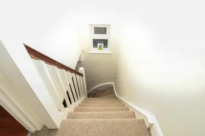 a staircase in a house with white walls and a stair case at 1 Tailors Cottage, Woodbridge in Woodbridge