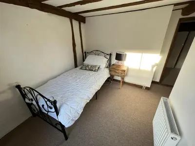 a small bedroom with a bed and a chair at 4 Bedroom townhouse on one of the oldest streets in Wymondham