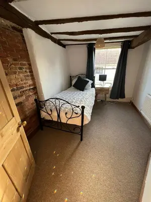 a bedroom with a bed in a room with a window at 4 Bedroom townhouse on one of the oldest streets in Wymondham