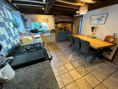 a kitchen and dining room with a stove and a table at 4 Bedroom townhouse on one of the oldest streets in Wymondham