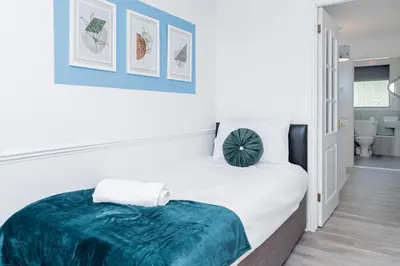 a bedroom with a bed with a green blanket on it at Modern and Spacious 4 Bedroom Home in Ipswich in Ipswich