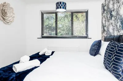 a bedroom with a bed with white sheets and a window at Modern and Spacious 4 Bedroom Home in Ipswich in Ipswich