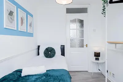 a bedroom with white walls and a bed with a blue blanket at Modern and Spacious 4 Bedroom Home in Ipswich in Ipswich