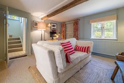 a living room with a white couch with two red pillows at Foxhole Cottage in Stowmarket
