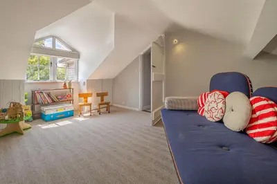 a living room with a blue couch and a play room at Foxhole Cottage in Stowmarket