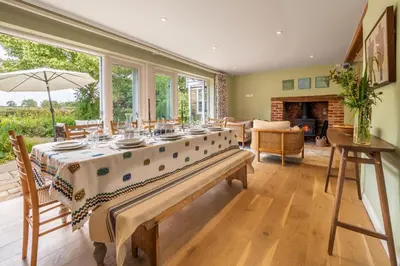 a large dining room with a table and a fireplace at Foxhole Cottage in Stowmarket