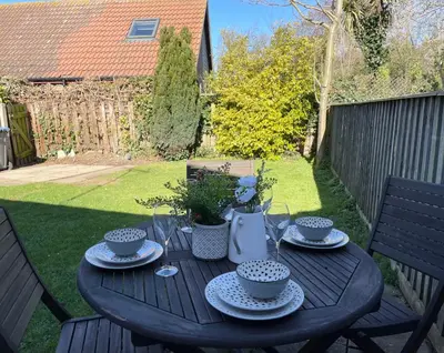 a wooden table with plates and glasses on a patio at Charming 2 Bedroom Bungalow with open plan living in Felixstowe