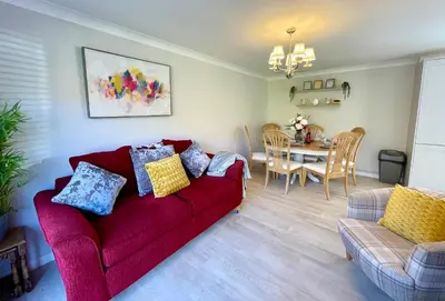 a living room with a red couch and a table at Charming 2 Bedroom Bungalow with open plan living in Felixstowe