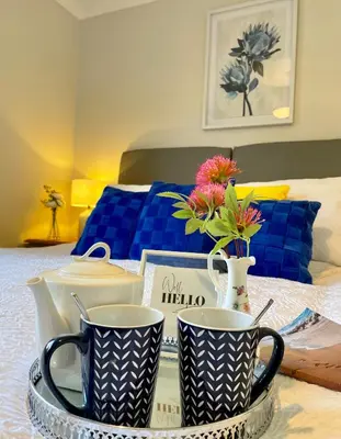 a table with two mugs on top of a bed at Charming 2 Bedroom Bungalow with open plan living in Felixstowe