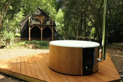 a hot tub on a wooden deck with a house at The Hive - beautiful studio with amazing hot tub in Cratfield