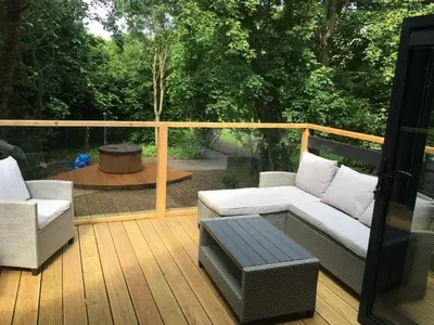 a deck with two chairs and a couch and a table at The Hive - beautiful studio with amazing hot tub in Cratfield