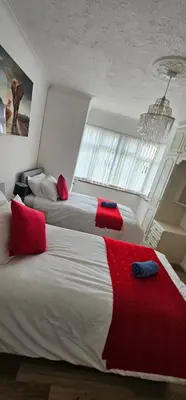 a bedroom with two beds with red pillows and a window at Contractors Home from Home in South Benfleet