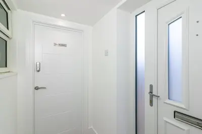 a white shower door in a bathroom with a window at King Pin Corner in Stevenage