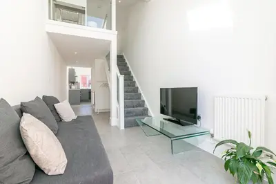 a living room with a gray couch and a television at King Pin Corner in Stevenage