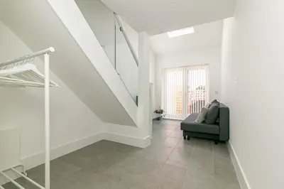 a living room with a staircase and a green chair at King Pin Corner in Stevenage