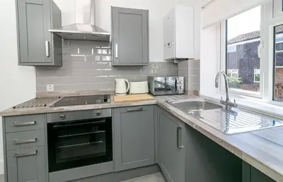 a kitchen with gray cabinets and a sink and a window at King Pin Corner in Stevenage