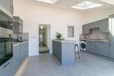 a large kitchen with gray cabinets and a sink at Archers House in Stevenage