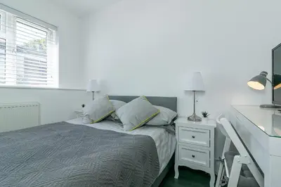 a white bedroom with a bed and a desk at Archers House in Stevenage
