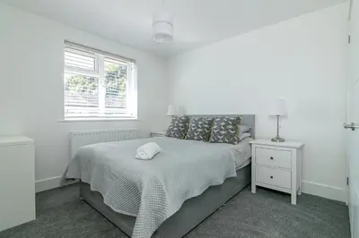 a white bedroom with a bed and a window at Archers House in Stevenage