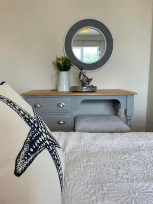 a bedroom with a bed with a dresser and a mirror at Luxurious Beach House with spectacular sea views in Felixstowe