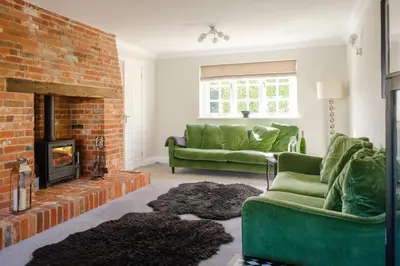 a living room with a green couch and a fireplace at Stripe Cottage - Aldeburgh Coastal Cottages in Aldeburgh