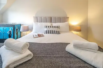 a bedroom with a large white bed with towels on it at Stripe Cottage - Aldeburgh Coastal Cottages in Aldeburgh