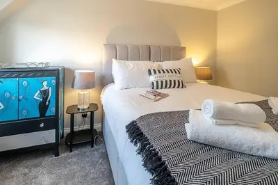 a bedroom with a large bed with a tv on it at Stripe Cottage - Aldeburgh Coastal Cottages in Aldeburgh