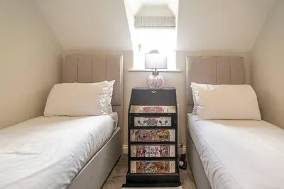 a bedroom with two beds and a book shelf between them at Stripe Cottage - Aldeburgh Coastal Cottages in Aldeburgh