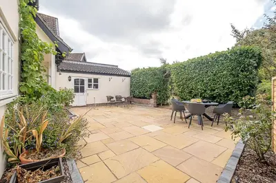 a patio with a table and chairs in a yard at Stripe Cottage - Aldeburgh Coastal Cottages in Aldeburgh