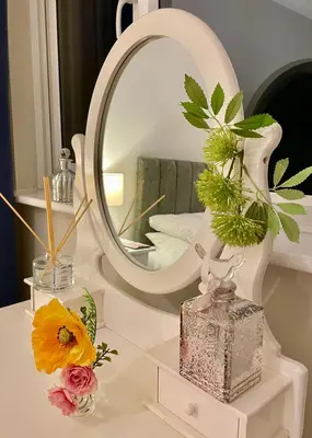 a mirror sitting on top of a table with flowers at Cosy Bungalow Near Open Countryside in Felixstowe