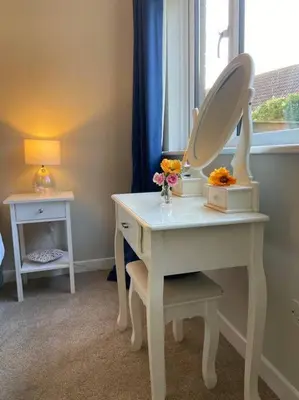 a white dressing table with a mirror and flowers on it at Cosy Bungalow Near Open Countryside in Felixstowe