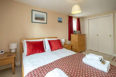 a bedroom with a large bed with red pillows at The Haven at Coastguard Court - Aldeburgh Coastal Cottages in Aldeburgh