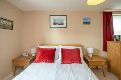 a bedroom with two red pillows on a bed at The Haven at Coastguard Court - Aldeburgh Coastal Cottages in Aldeburgh