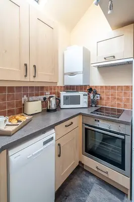 a kitchen with white cabinets and a stove top oven at The Haven at Coastguard Court - Aldeburgh Coastal Cottages in Aldeburgh
